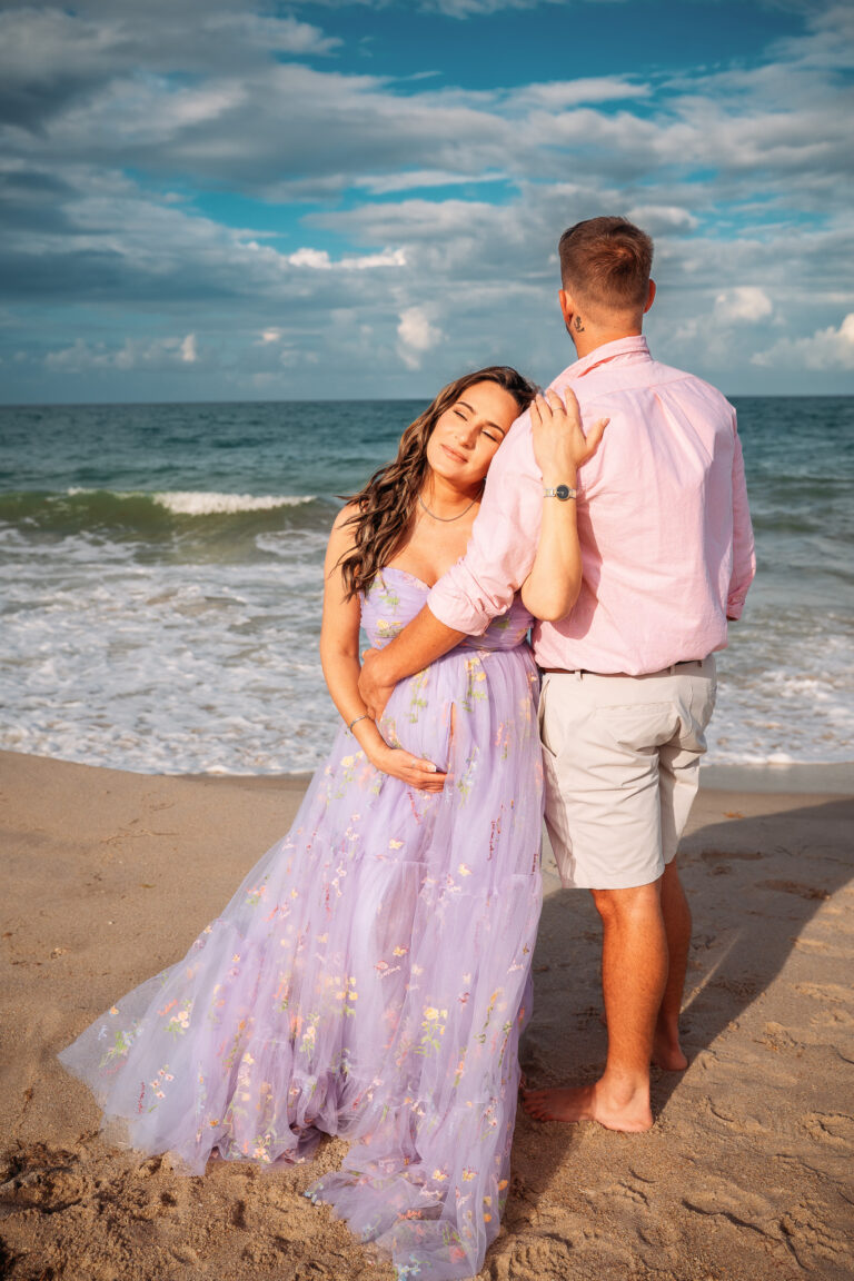 Couple standing on the beach Pregnant woman in lavender maternity gown smiling on the beach in Vero Beach, Florida