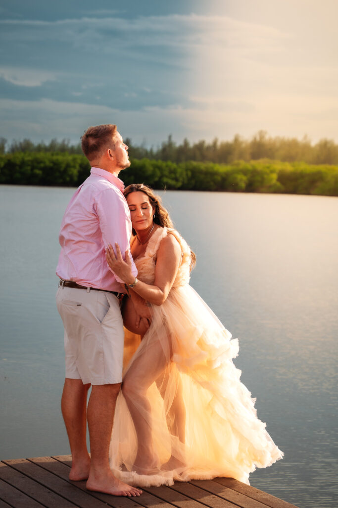 Expecting parents sharing a quiet moment on the dock at sunset in Vero Beach